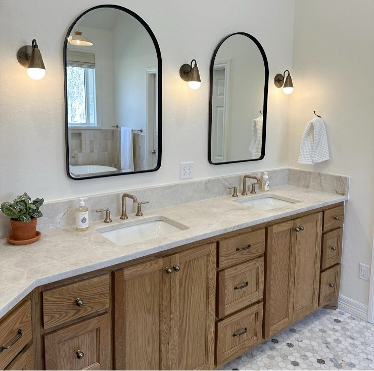 A rustic wooden bathroom vanity with two white sinks and faucets, set over a gray mosaic tile floor.