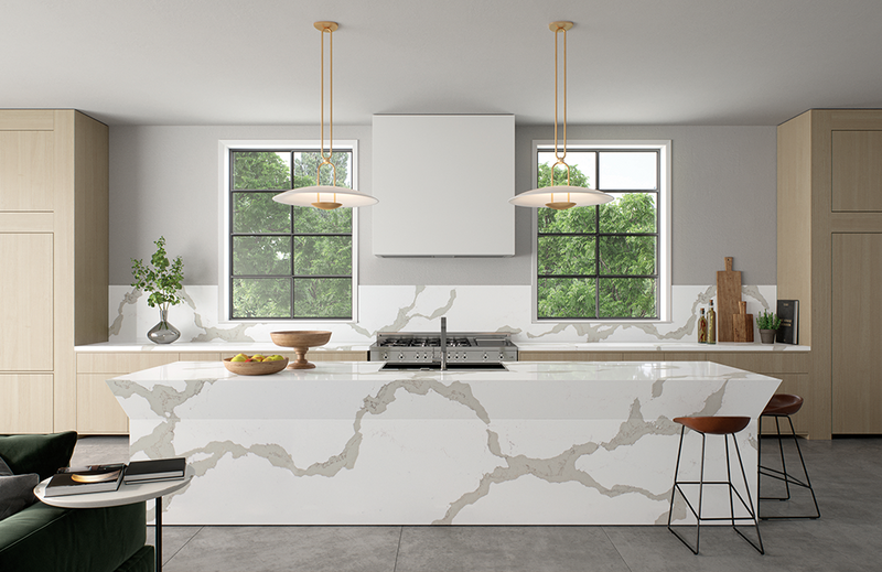 Contemporary kitchen with bold-veined quartz waterfall island, brass pendants and light oak cabinets
